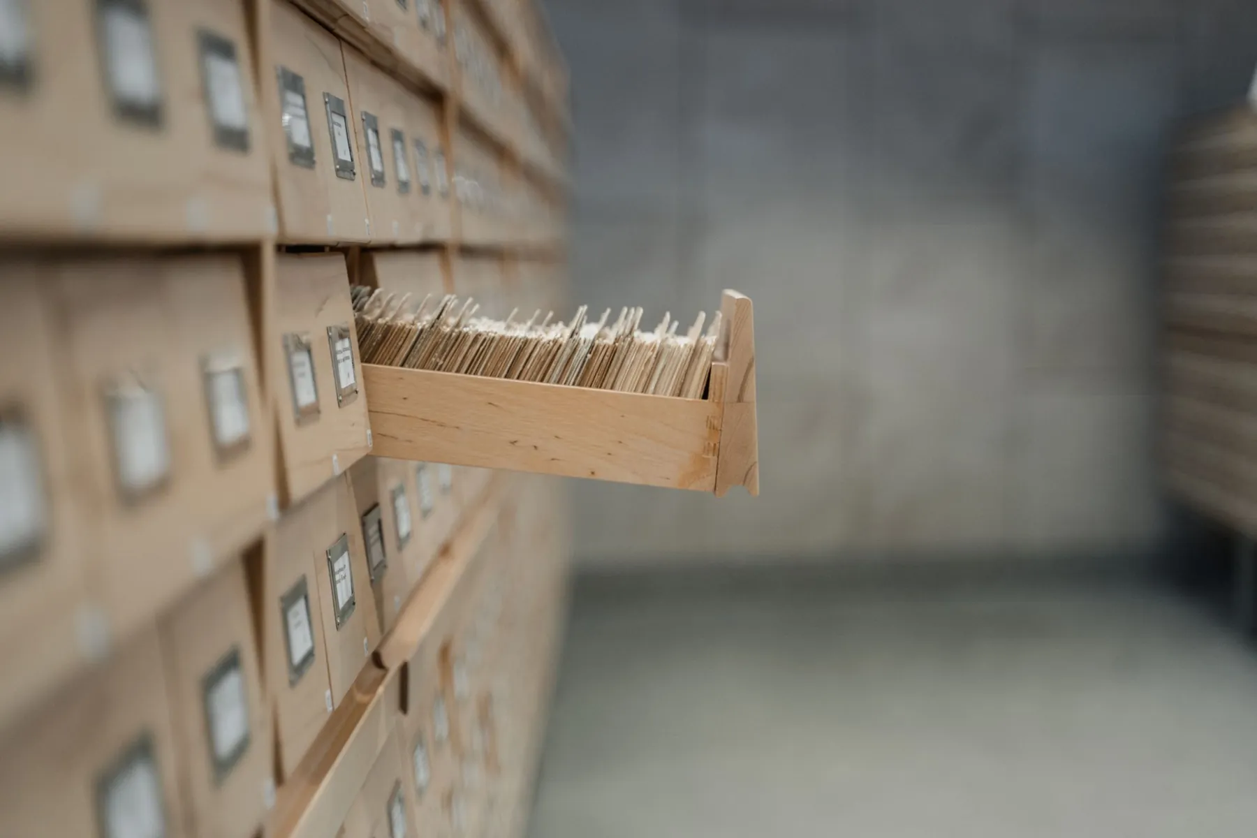 An open drawer in a wall of wooden card catalogs.