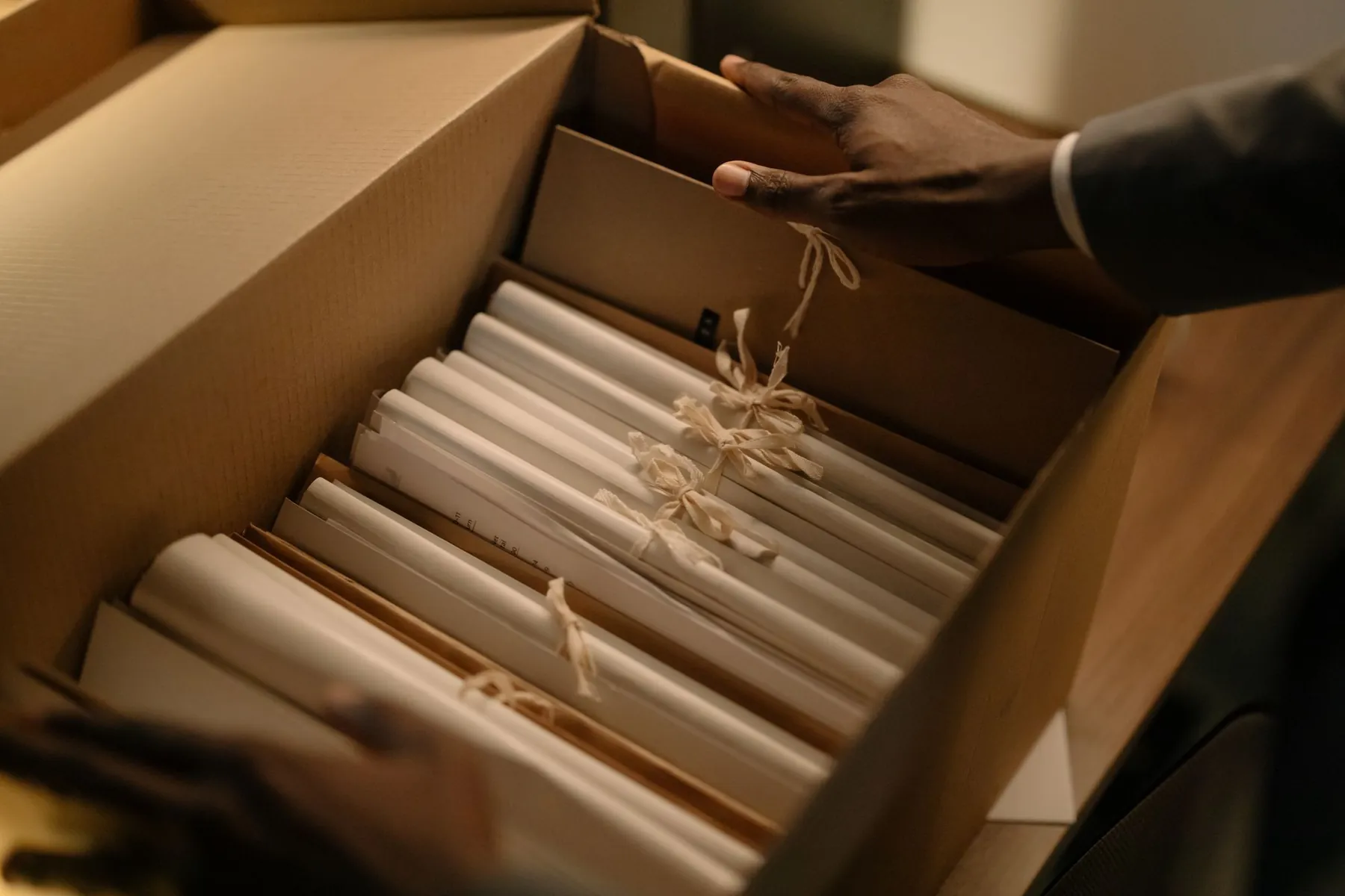 Hands going through a box of files tied with string.