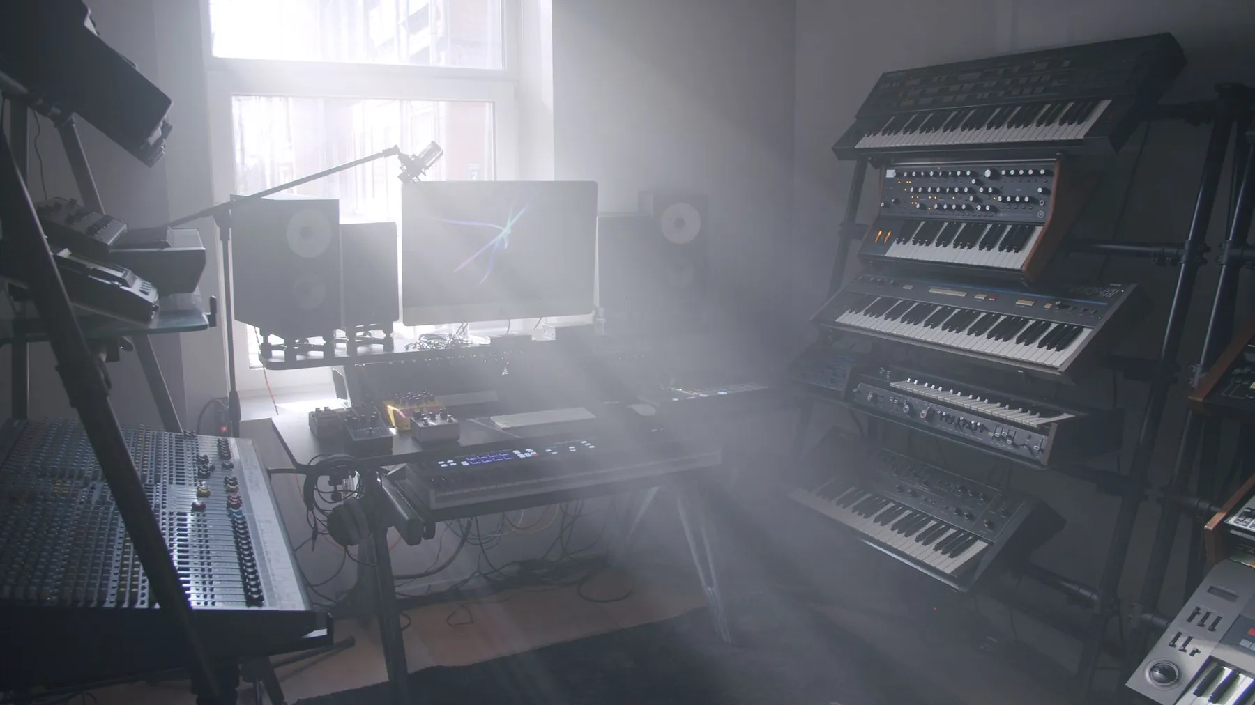 A room full of synthesizers and speakers in soft morning haze.