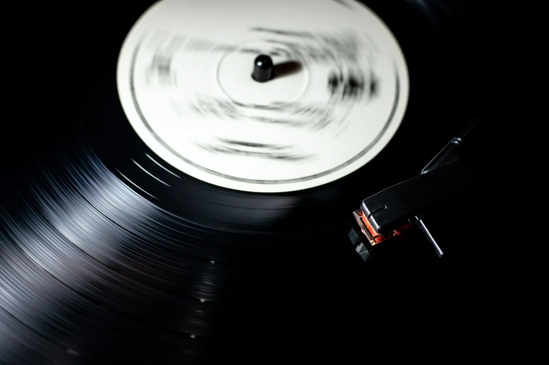 A vinyl record spinning on a turntable, the tonearm resting on it.