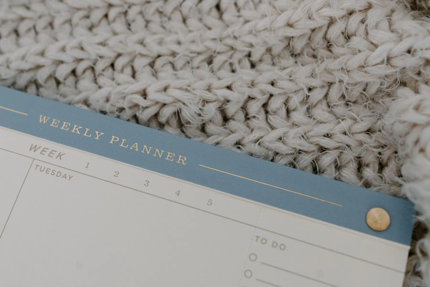 A weekly planner resting on a knitted blanket.